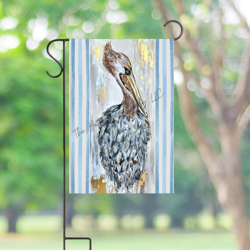 Pelican Rita coastal garden flag waving in a beautifully landscaped garden with lush greenery.